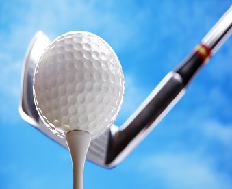 Golf club and golf ball about to tee off against a blue sky