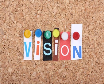 The word Vision in cut out magazine letters pinned to a cork notice board as a concept for success in business